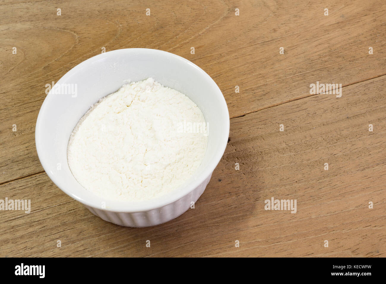 Mehl von Weizen aus weisser Keramik Schüssel, ramekin, Mitte links, auf hölzernen Tisch Stockfoto