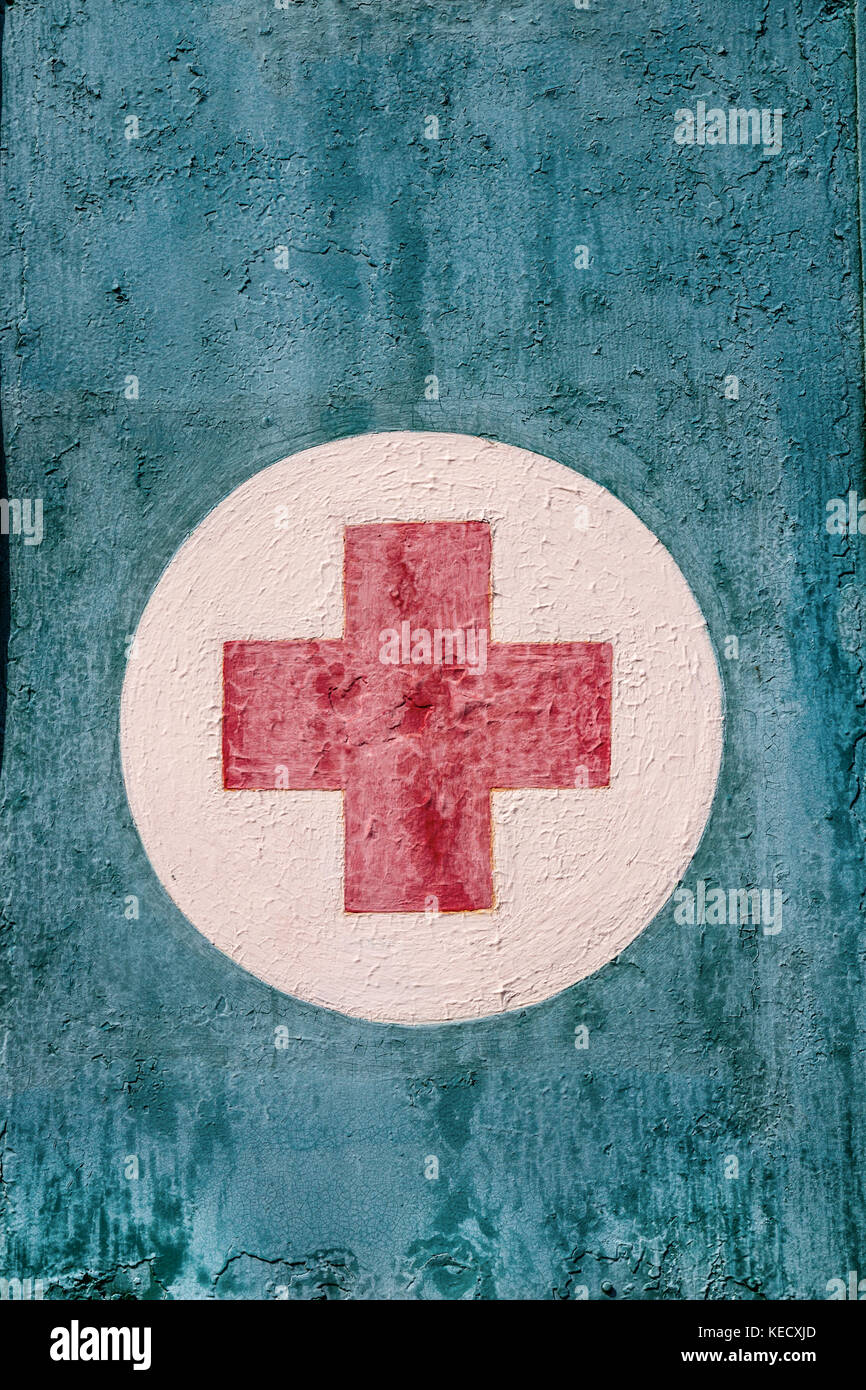 Verwittert, rot lackiert Kreuz auf weißem Cirkel gegen eine hellblaue Hintergrund. Stockfoto