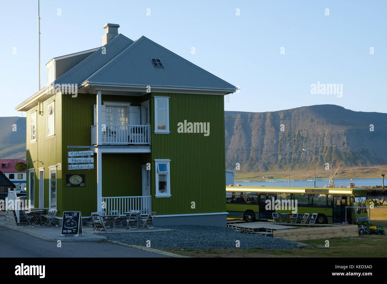 Green Cafe Gebäude Simbahollin, alter Bus, zwei Veranden, Berge und blauer Himmel in der abgelegenen Stadt Thingeyri Dýrafjoerður Westfjorde Nord-Island Stockfoto