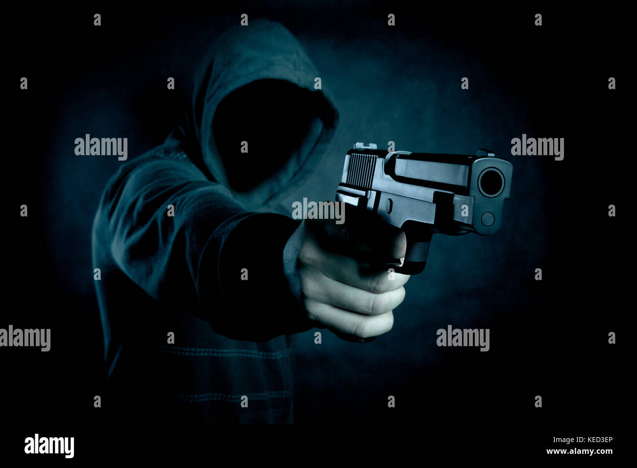 Mit Kapuze Mann mit einer Pistole in der Dunkelheit Stockfoto