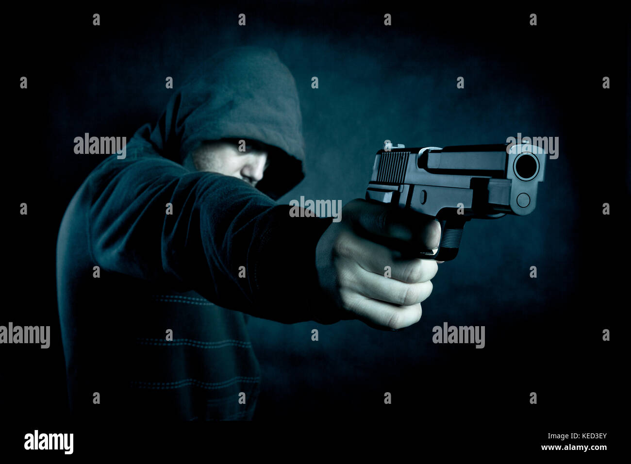 Mit Kapuze Mann mit einer Pistole in der Dunkelheit Stockfoto