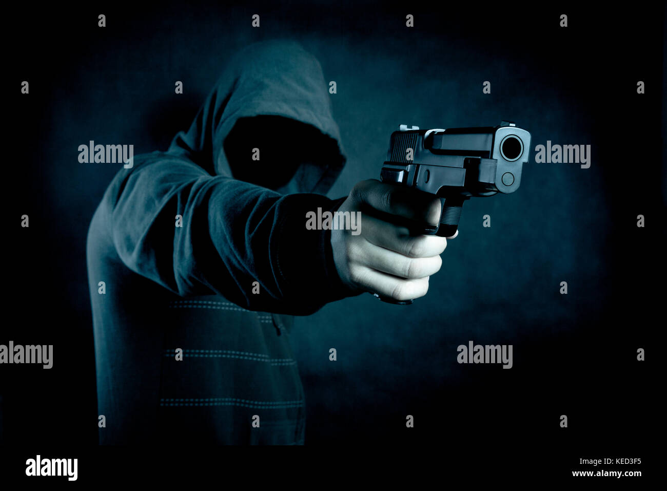 Mit Kapuze Mann mit einer Pistole in der Dunkelheit Stockfoto