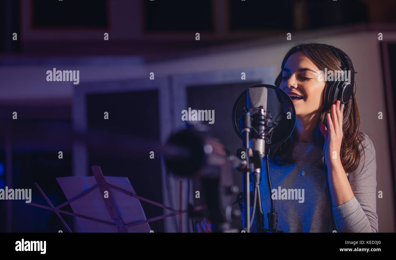 Weibliche Sänger Wiedergabe Aufnahme Album im professionellen Studio. Frau singen ein Lied in Music Recording Studio. Stockfoto