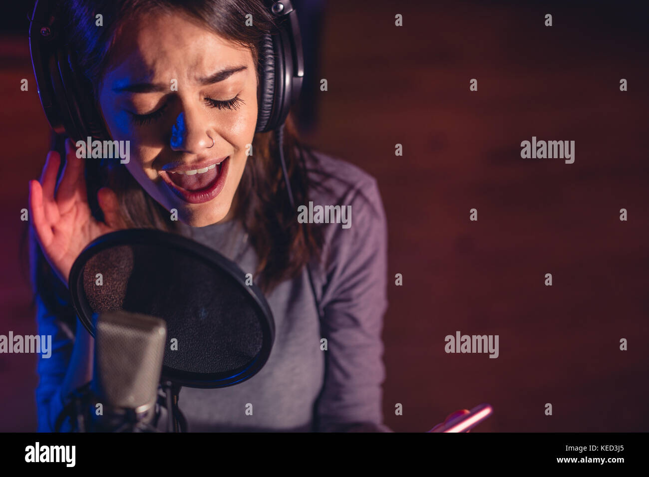 In der Nähe der weiblichen Sänger Singen in ein Mikrofon. Junge Frau Musik Künstler ein Lied singen im Studio. Stockfoto