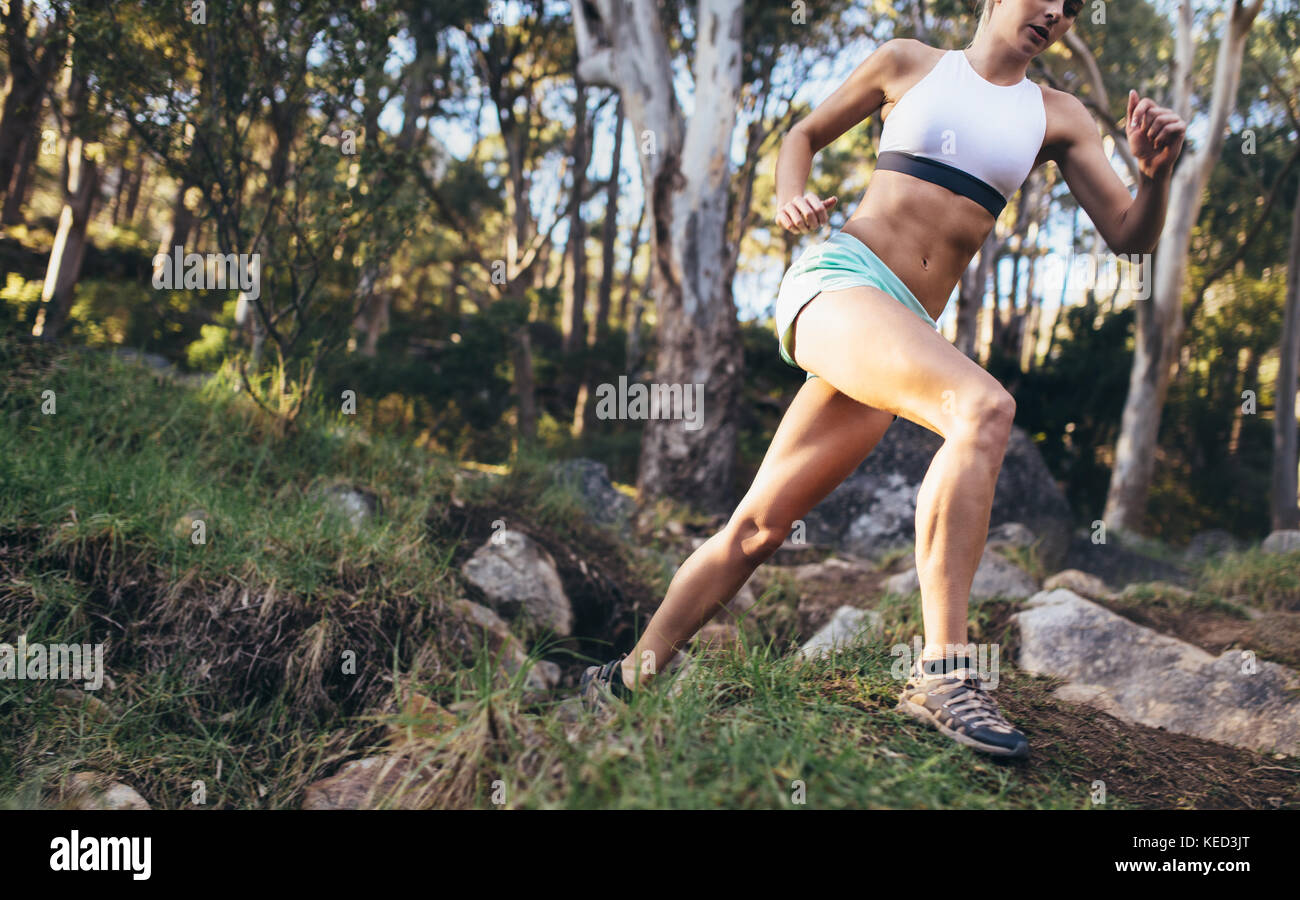 Die Frau, die durch Felsen und harte Oberfläche. Athletische Frau läuft auf einem Gelände im Wald. Stockfoto
