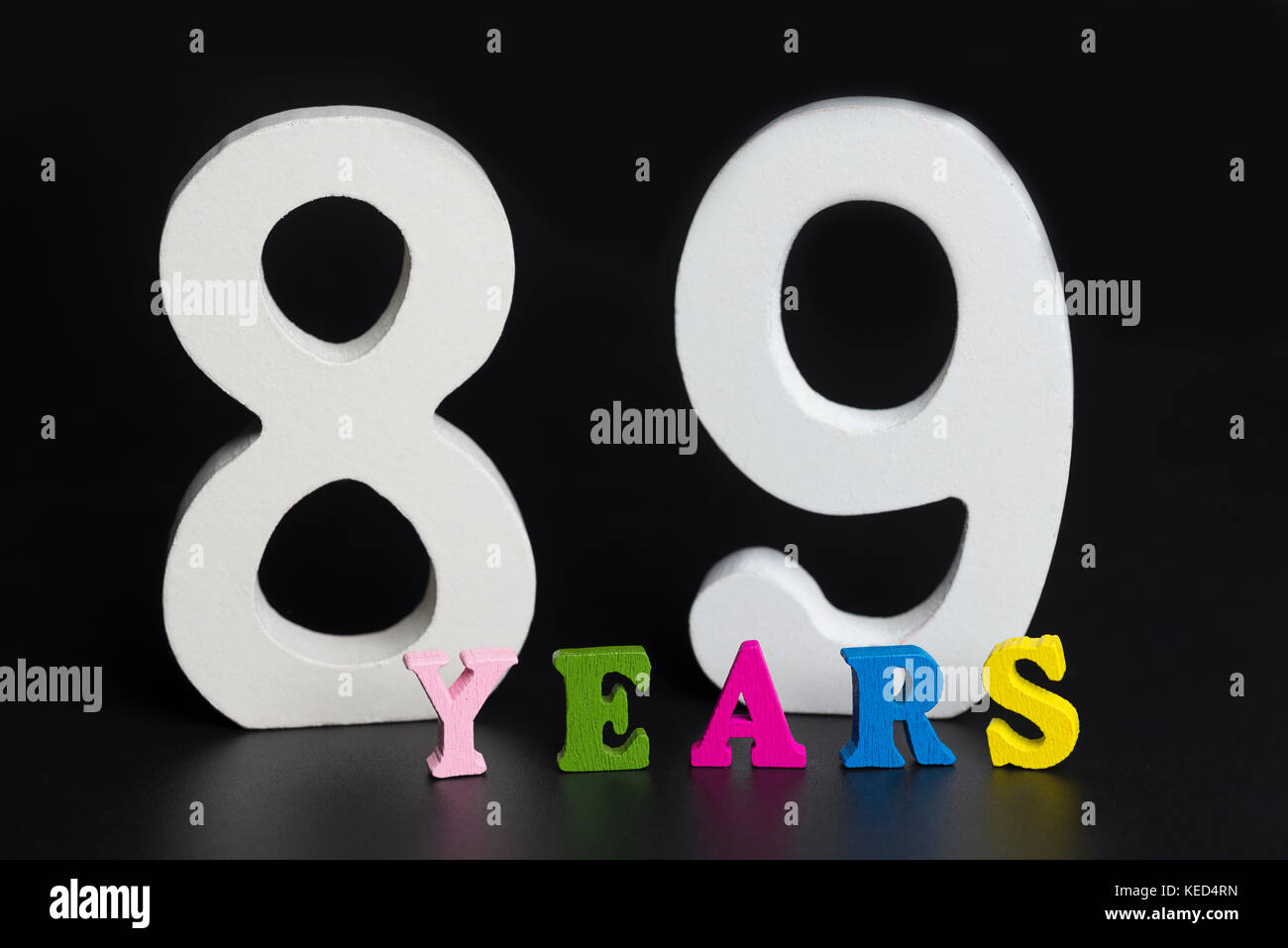 Buchstaben und Zahlen 89 Jahre alt auf einem schwarzen Hintergrund isoliert. Stockfoto