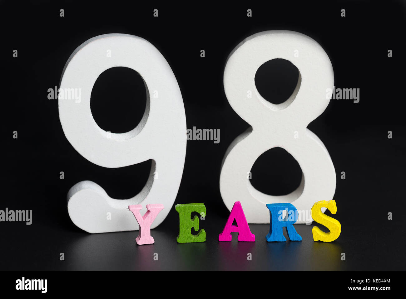 Buchstaben und Zahlen 90 - acht Jahre auf einem schwarzen Hintergrund isoliert. Stockfoto