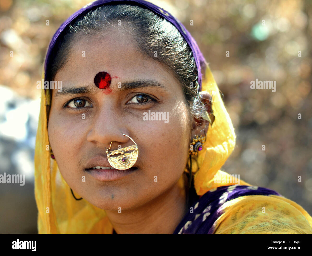Kopfschuss einer jungen Gujarati-Frau mit gelbem Dupatta und wertvollem, traditionellem indischem Nasenstiel Stockfoto