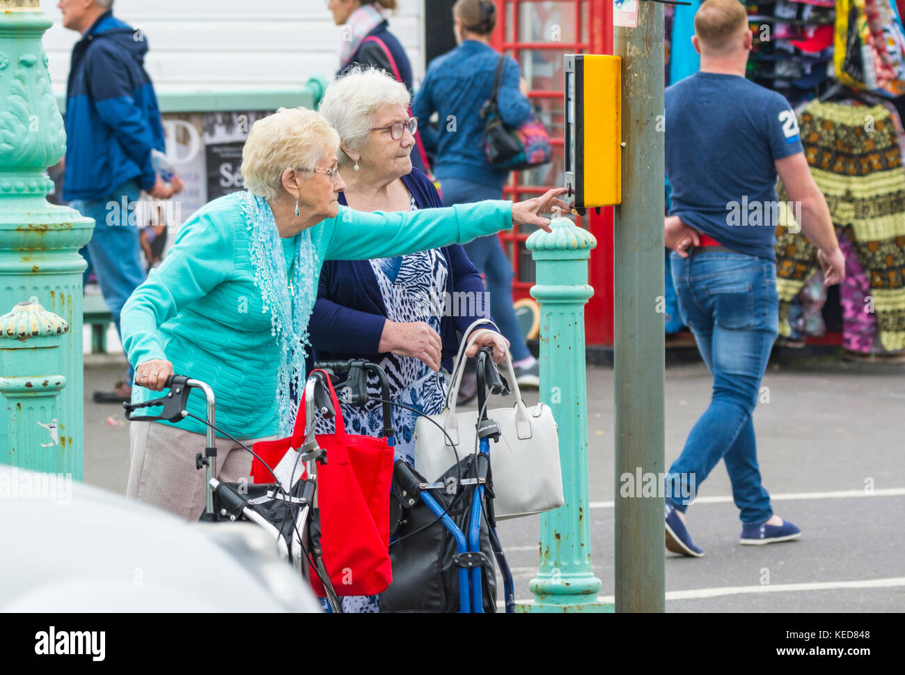 Ältere Frau durch Drücken der Taste auf ein Pelikan Überqueren der Straße in Brighton, East Sussex, England, UK zu überqueren. Stockfoto