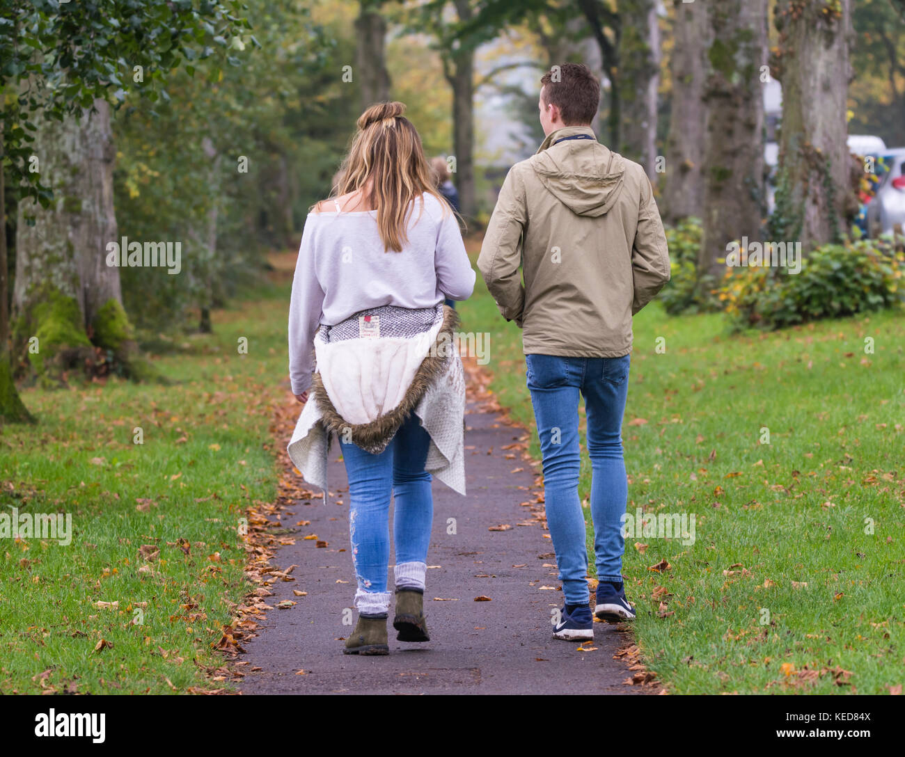 Junges Paar suchen Hinter gehen auf einem Feldweg, der im Herbst in Großbritannien. Stockfoto