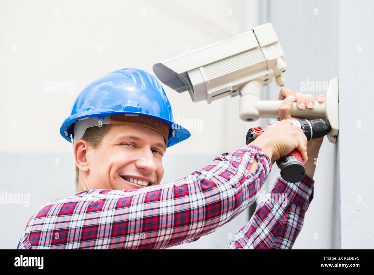Nahaufnahme der Glücklichen männlichen Techniker installieren die Kamera an der Wand Stockfoto