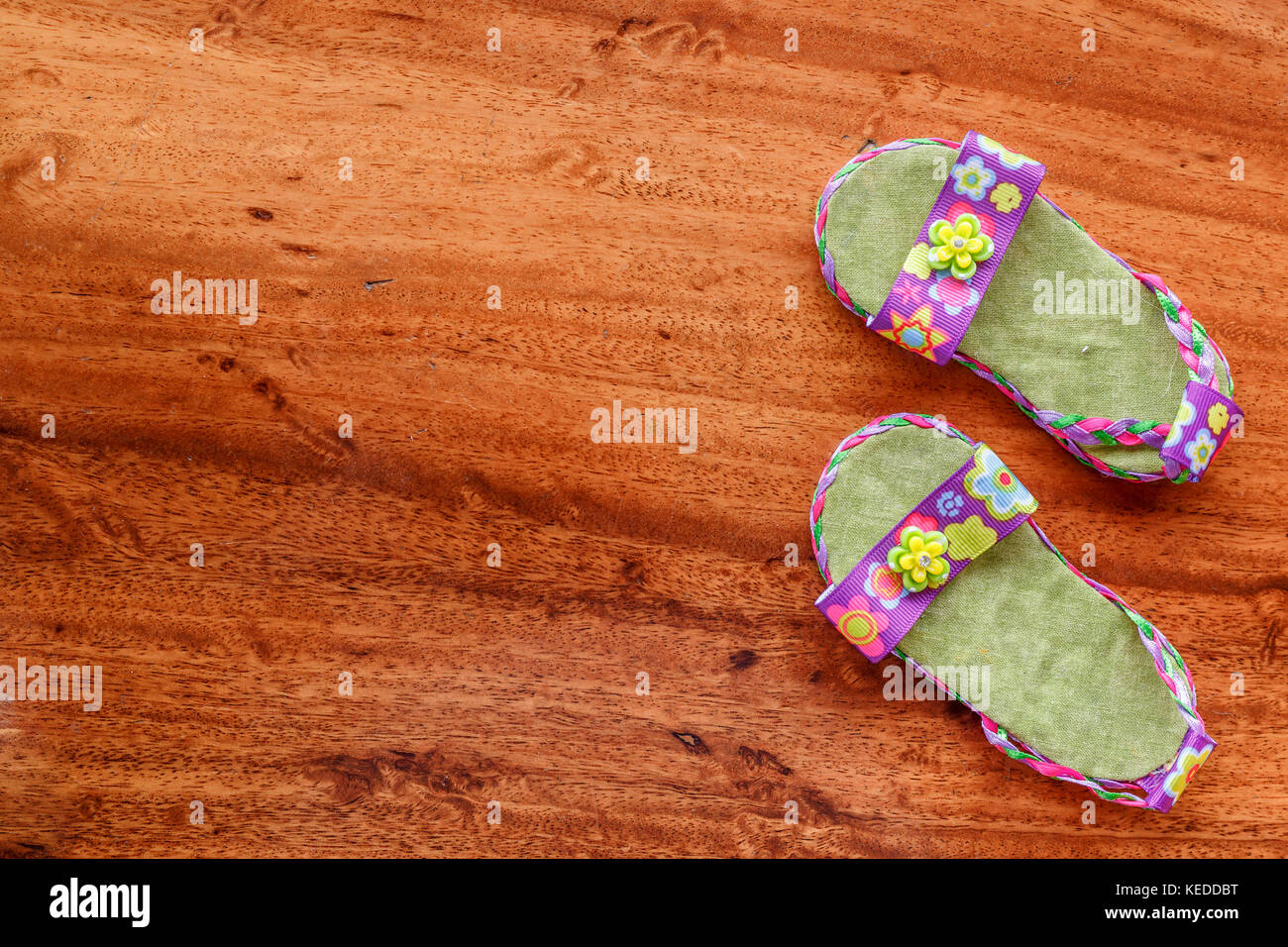 Lila baby Sandalen gegen eine holzmaserung Hintergrund angeordnet. minimalistischen Stil aussehen. Stockfoto