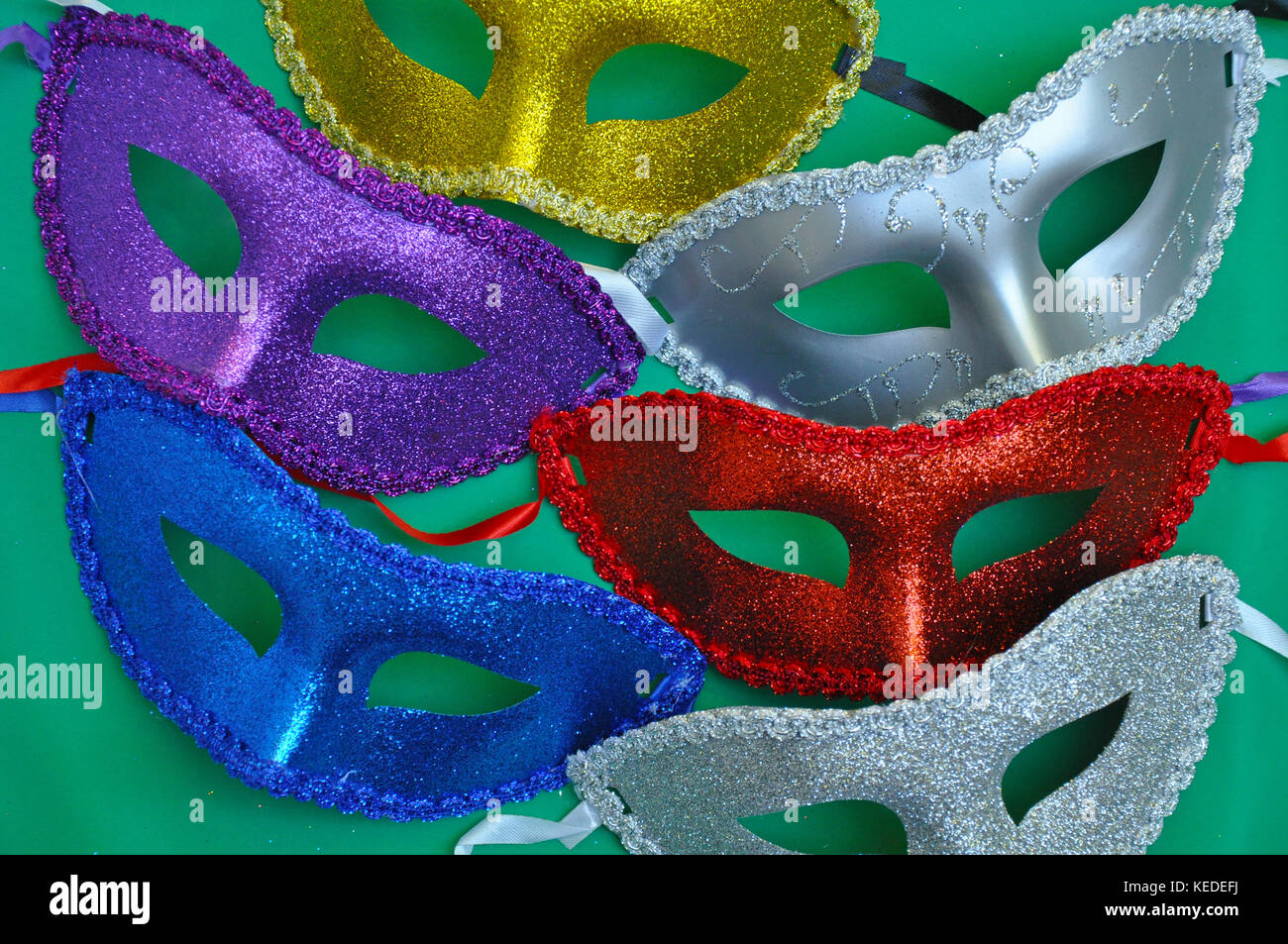 Bunte glitzernde Masken auf grünem Hintergrund Stockfoto