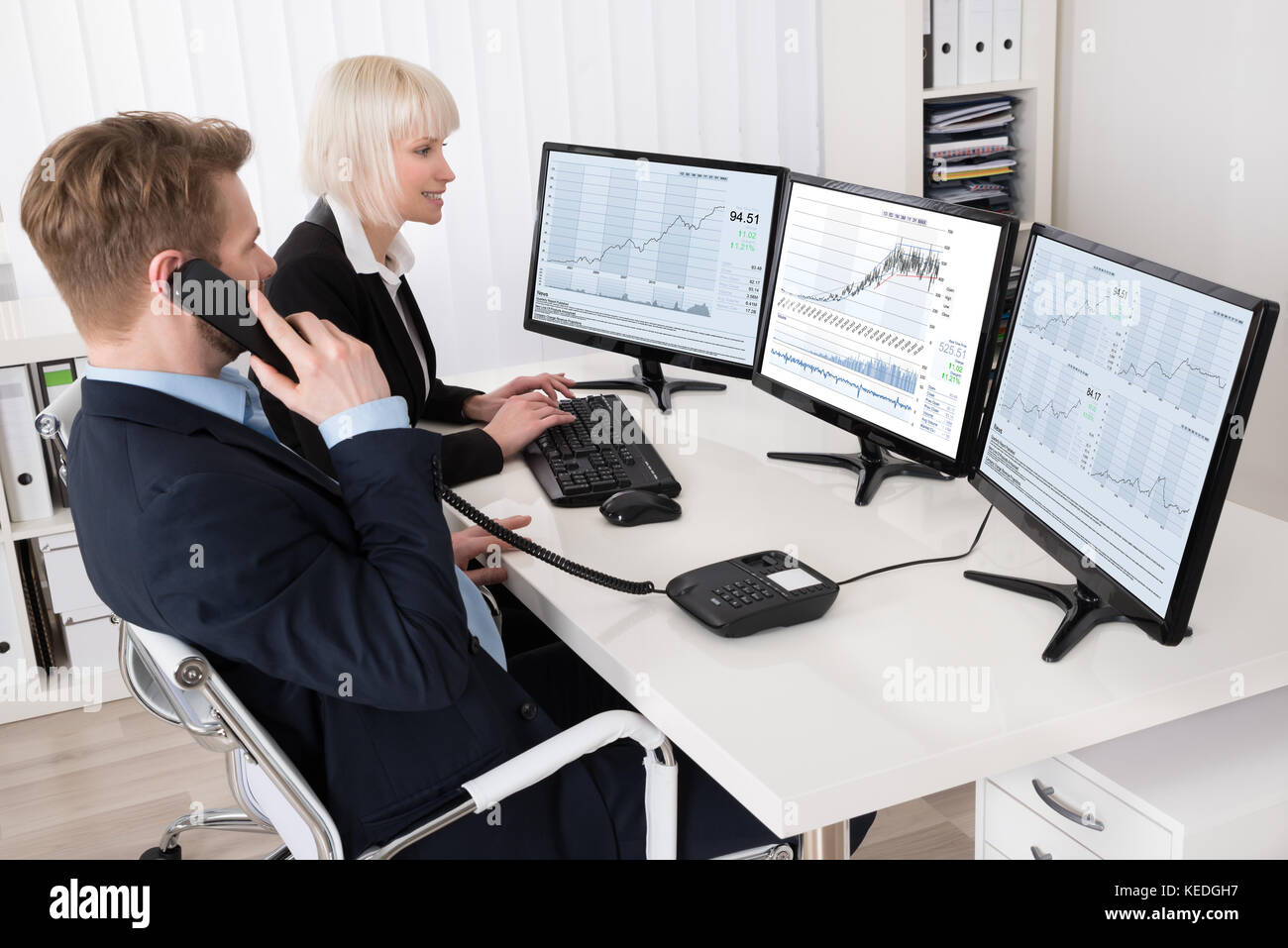 Zwei Geschäftsleute Analyse Stock Charts auf mehreren Bildschirmen Stockfoto