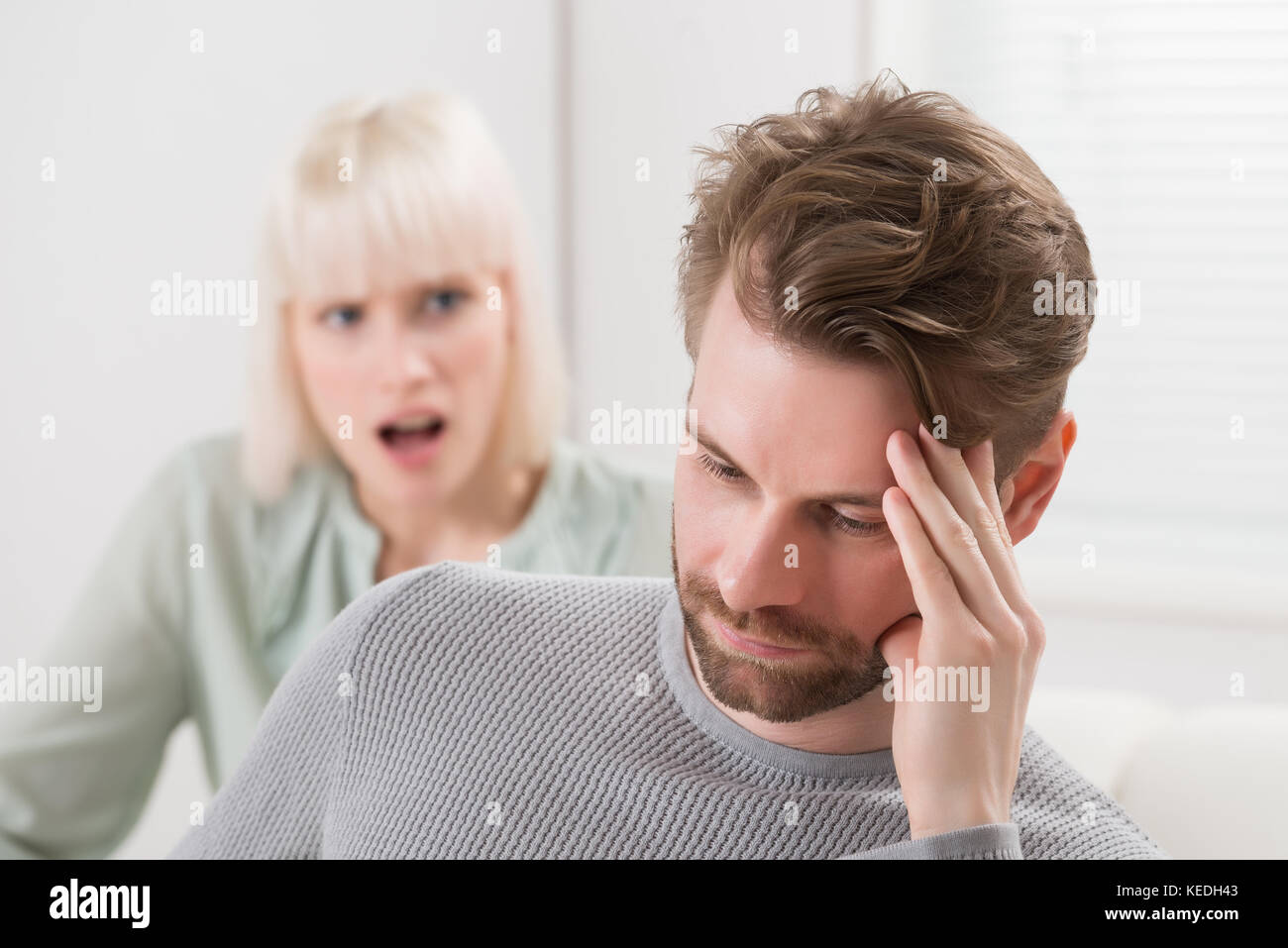 Unglückliche Frau sitzt auf einem Sofa zu schreien die frustrierter Mann Stockfoto