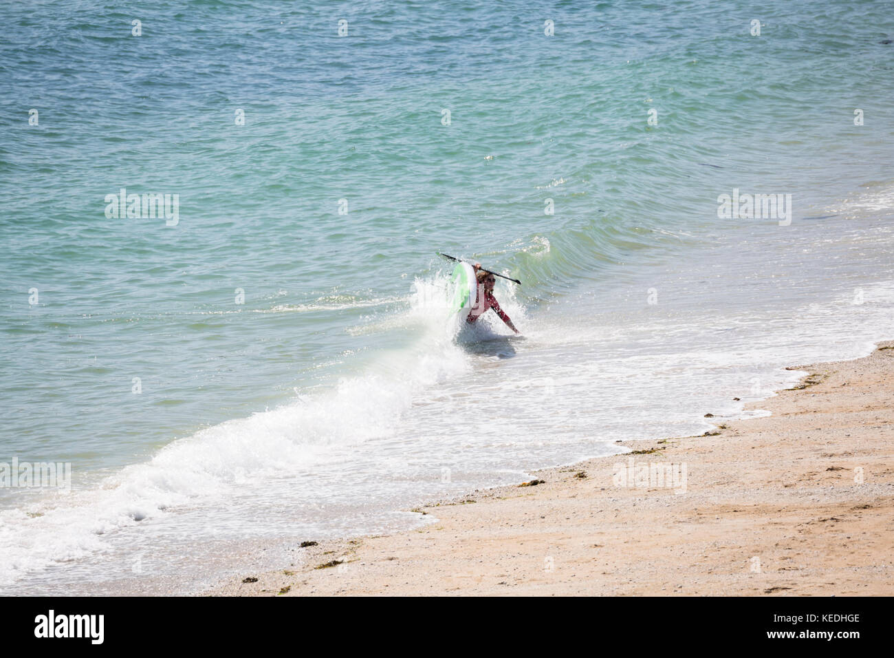 Paddel boarder fallen weg in surf Stockfoto