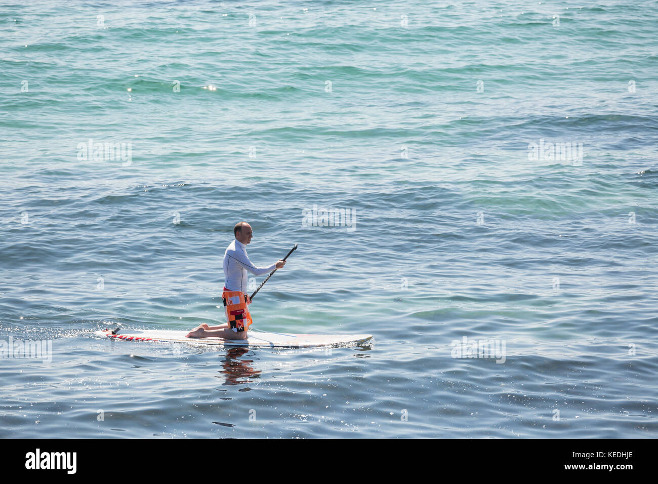 Stand Up Paddle boarder kniend Paddel Stockfoto
