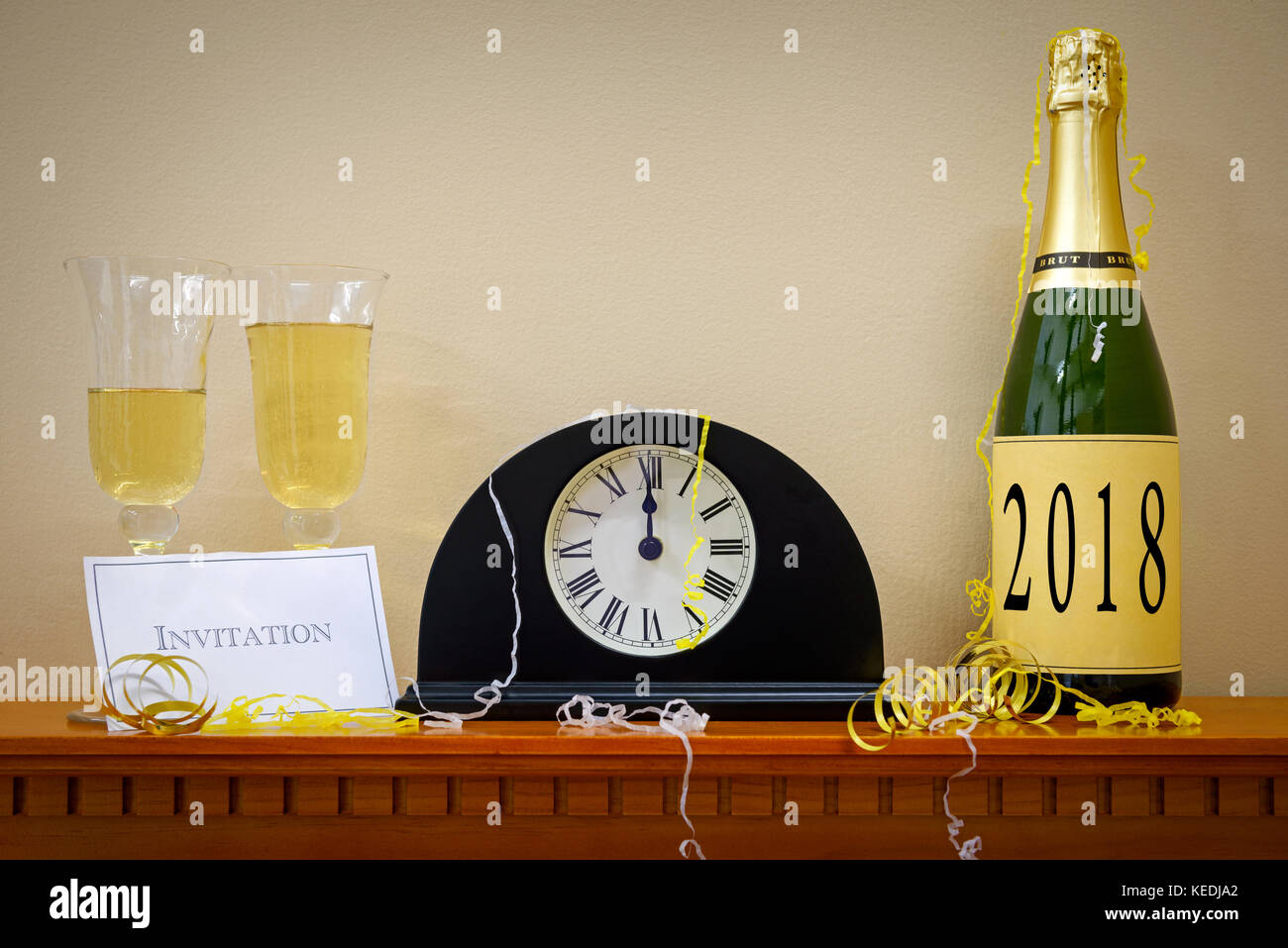 Eine Uhr, die Mitternacht in das neue Jahr mit einer Flasche Champagner mit der Bezeichnung 2018, Gläser und Einladung von Streamer umgeben. Stockfoto