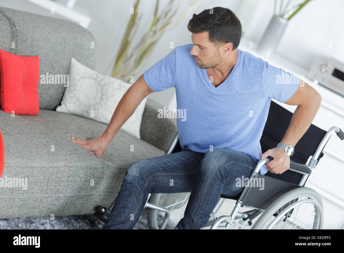 Mann im Rollstuhl sitzen Sofa alon e Stockfoto