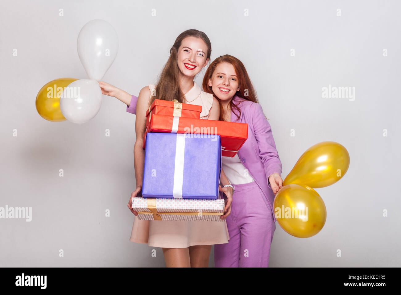 Zwei schöne Mädchen, dass Geschenke Box und Heißluftballon haben ein Glück sehen und zeigt ein v-Zeichen an Kamera. studio Shot Stockfoto
