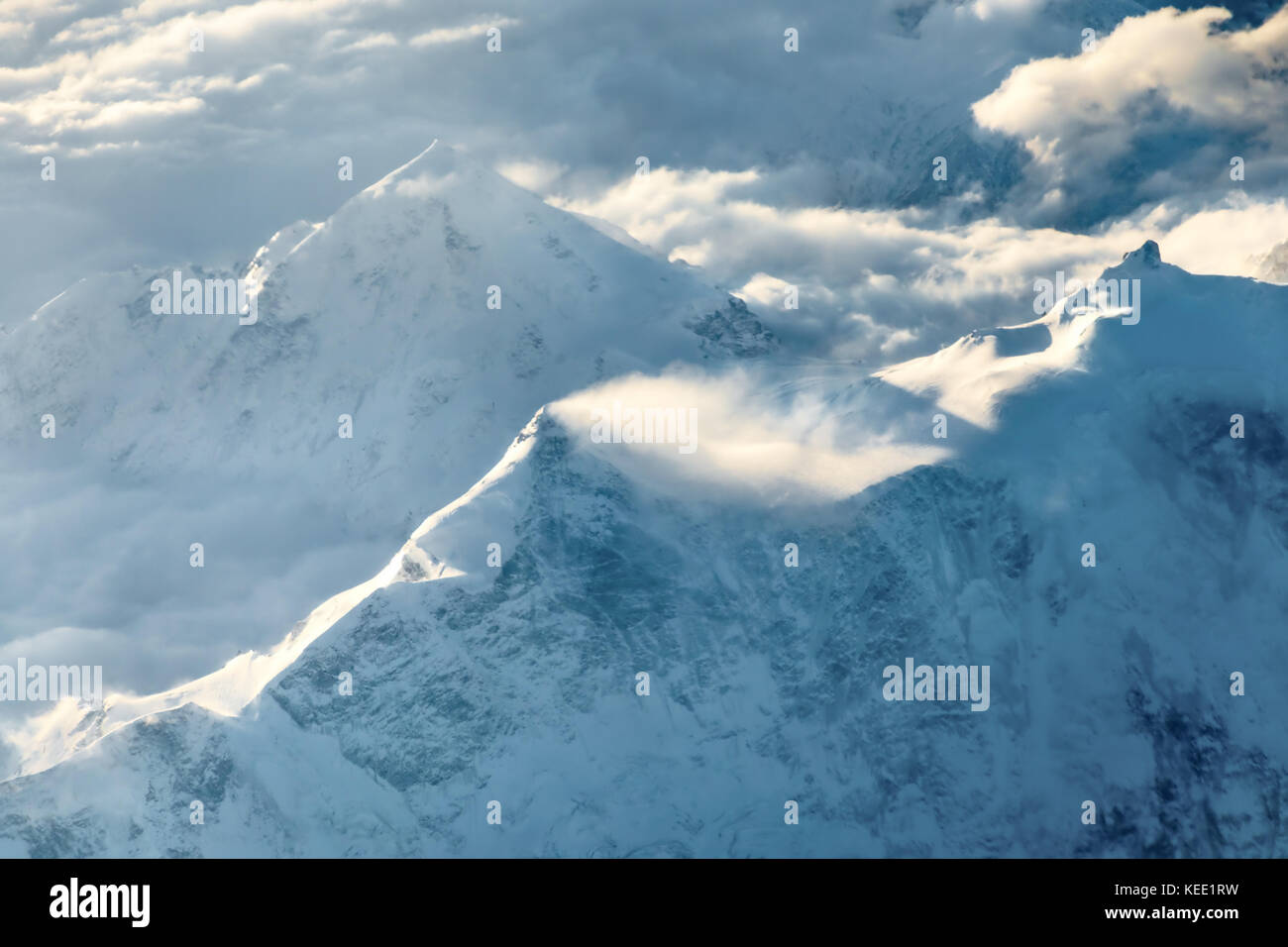 Die schneebedeckten Gipfel der Berge in den Wolken. Blick von oben. Stockfoto