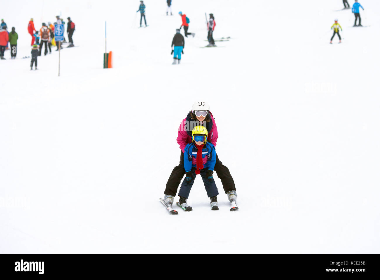Süße junge und seine Mutter, auf einer milden Skipiste im österreichischen Skigebiet an einem bewölkten Tag Skifahren lernen Stockfoto