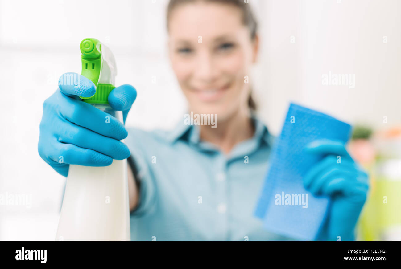 Lächelnden jungen Hausfrau, Hausarbeiten und Spritzen ein Reinigungsmittel, Hand- und Flasche, selektiven Fokus Stockfoto