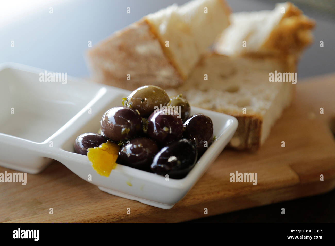 Oliven und Brot - Nahaufnahme auf Holzbrett Stockfoto
