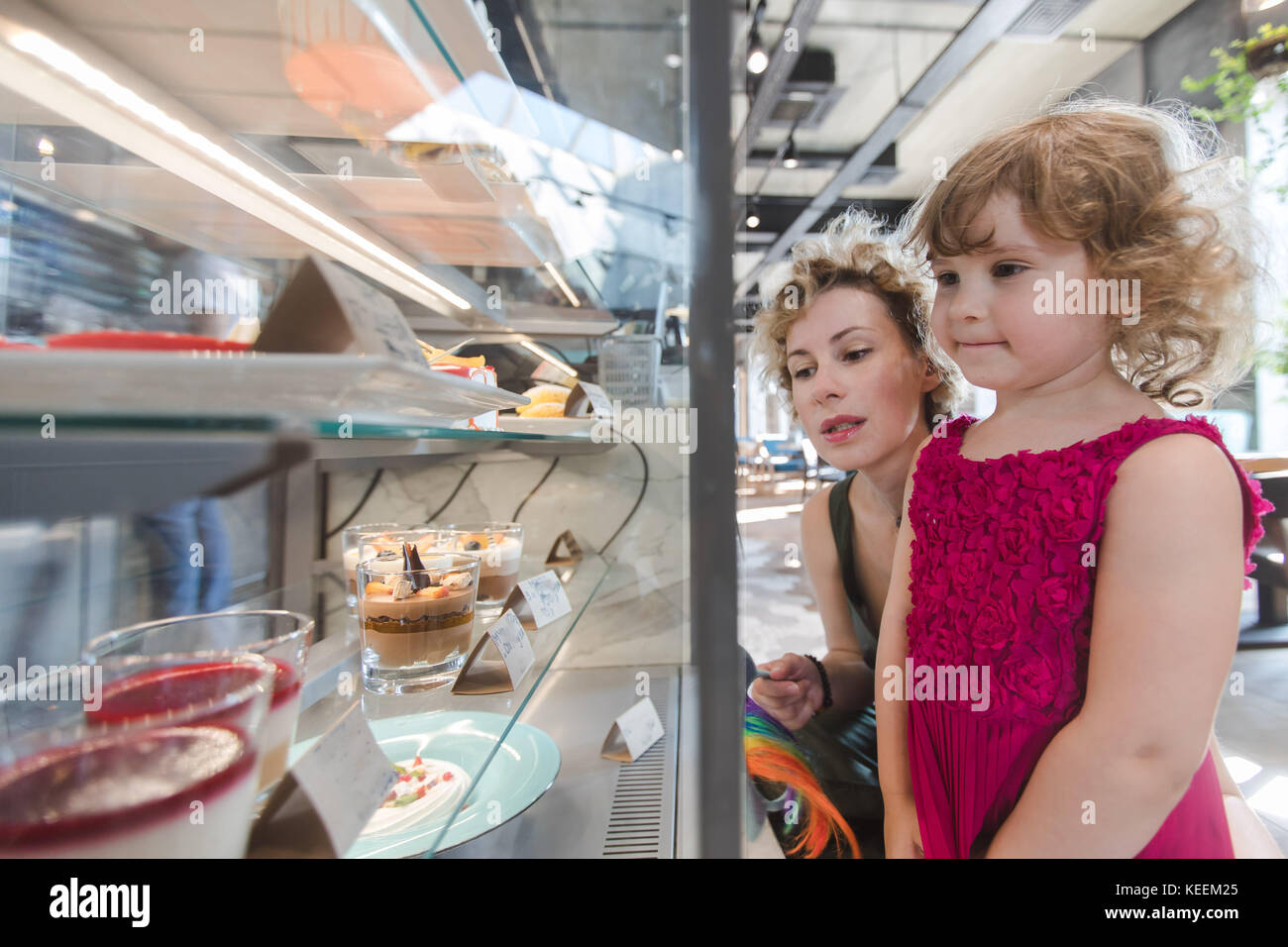Mädchen und Mutter sammeln Süßigkeiten in Cafe Stockfoto