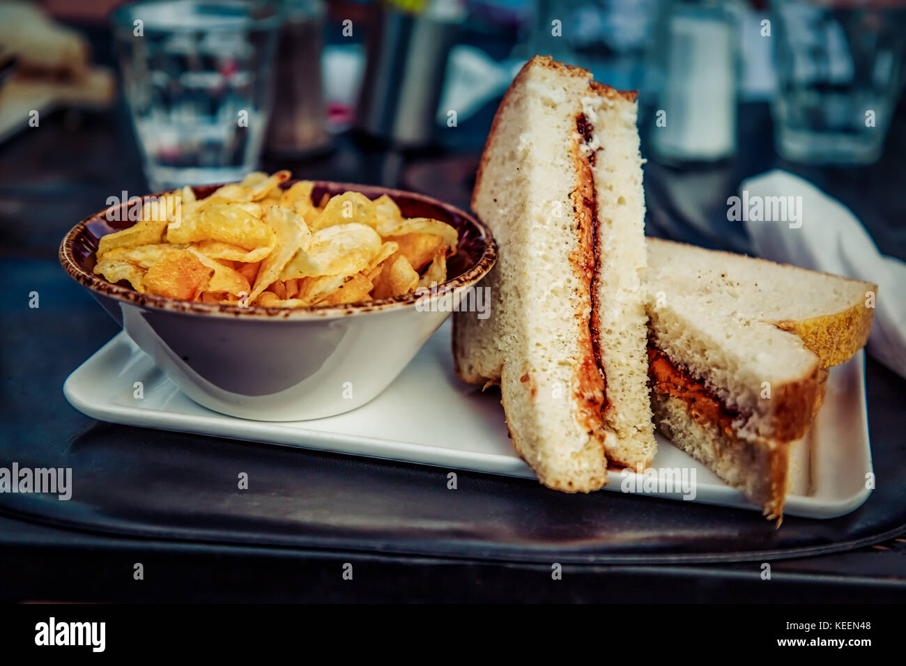 Ein Erdnussbutter und jelly Sandwich mit frischem Weißbrot zubereitet und mit einer Seite der Kartoffelchips. Oh ja… Stockfoto
