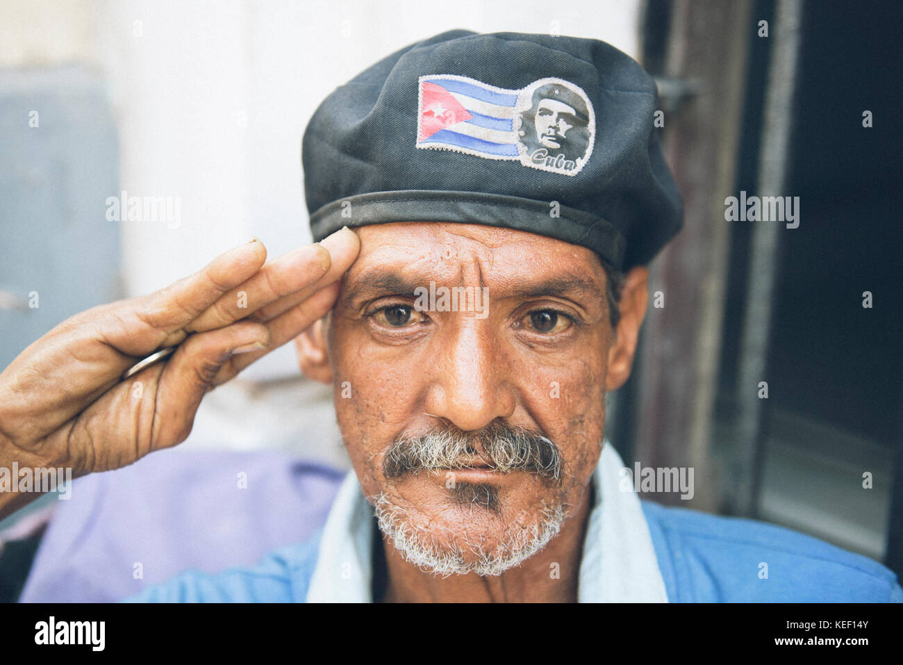 Patriotische kubanischen Mann begrüßt wie ein Soldat beim Tragen einer Kappe mit einer kubanischen Flagge und Bild des Che Guevara. Stockfoto