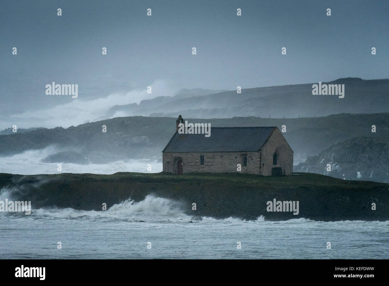 Sturmwind Teig St Cwyfan's Church und die Küstenlinie, Anglesey, North Wales, UK Stockfoto