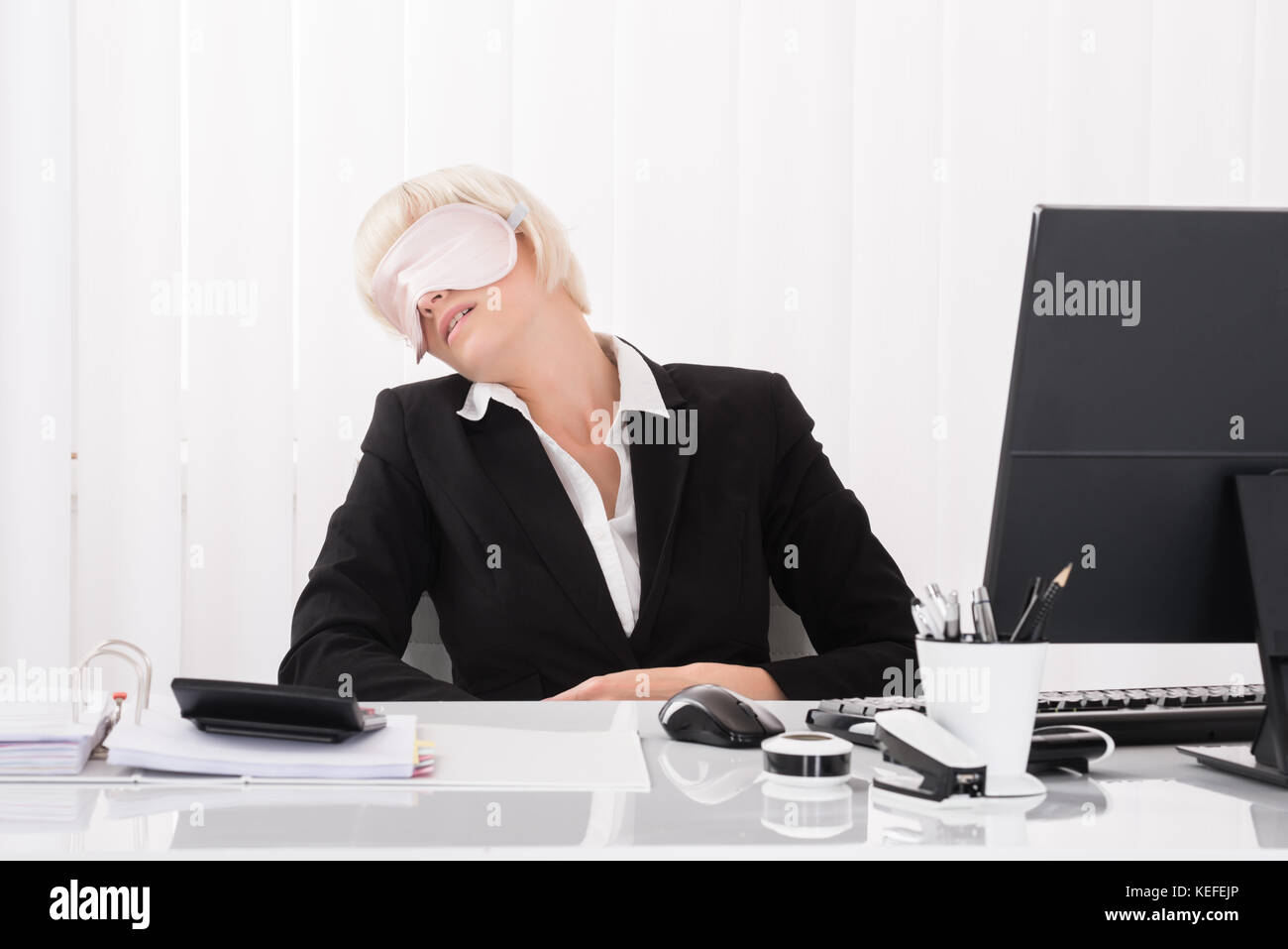 Junge Geschäftsfrau tragen Schlafmaske und Schlafen im Büro Stockfoto