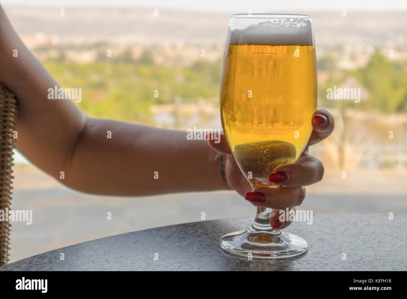 Woman's Hand ein Glas Bier, mit der Natur in verschwommenen Hintergrund. Stockfoto