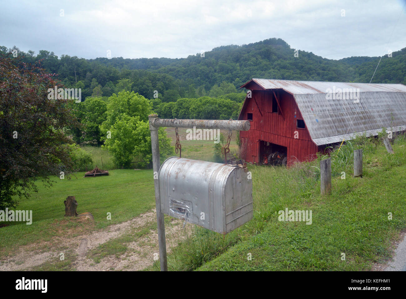 Rote Scheune und ein grauer Briefkasten in einer ländlichen Szene in Kentucky mit den Appalachen im Hintergrund. Stockfoto