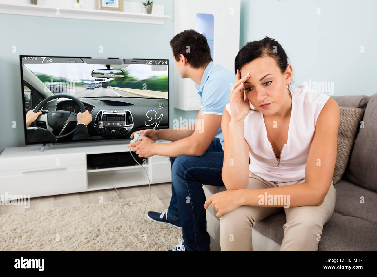 Frau sitzt neben ein beschäftigter Mann süchtig nach dem Spiel zu Hause im Fernsehen umgekippt Stockfoto