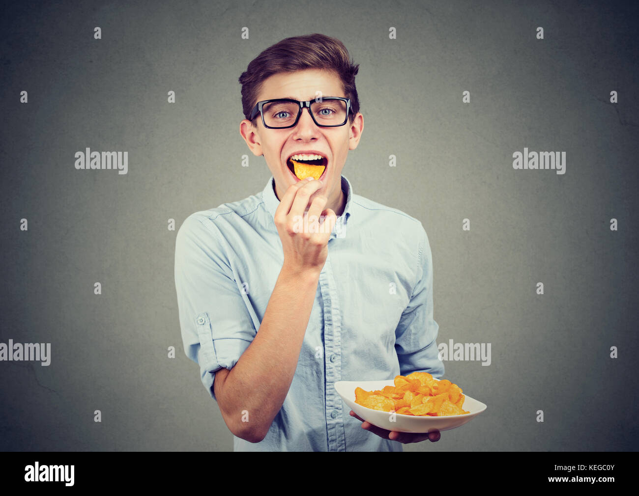 Junger Mann essen Kartoffelchips Stockfoto