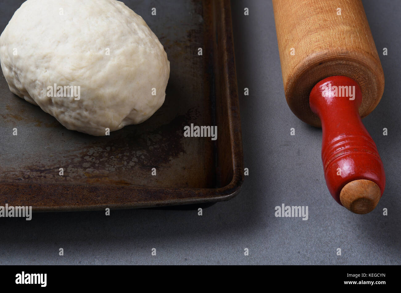 Nahaufnahme von einer Kugel des raw Brot Teig auf ein Backblech mit einem Holz Rolling Pin. Stockfoto