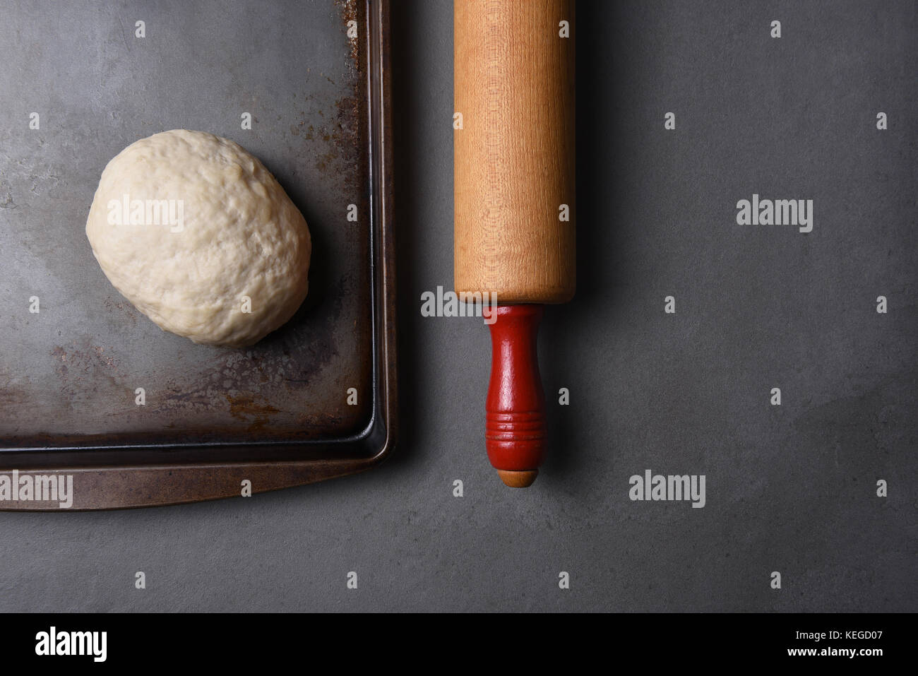 Blick von oben auf eine Kugel von raw Brot Teig auf ein Backblech mit einem Holz Nudelholz mit kopieren. Stockfoto
