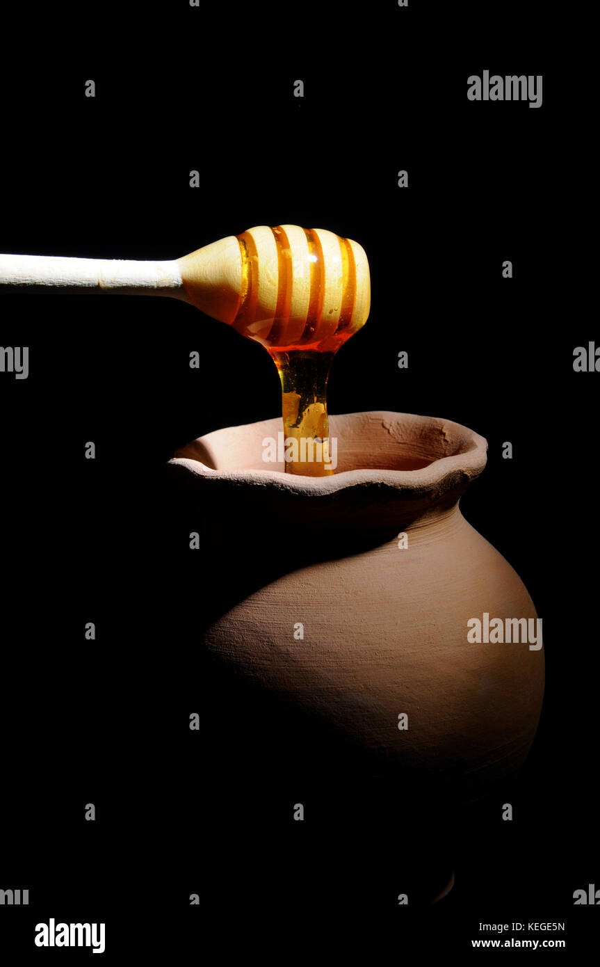 Honey Pot mit Honig Pendelarm schwarzer Hintergrund Stockfoto