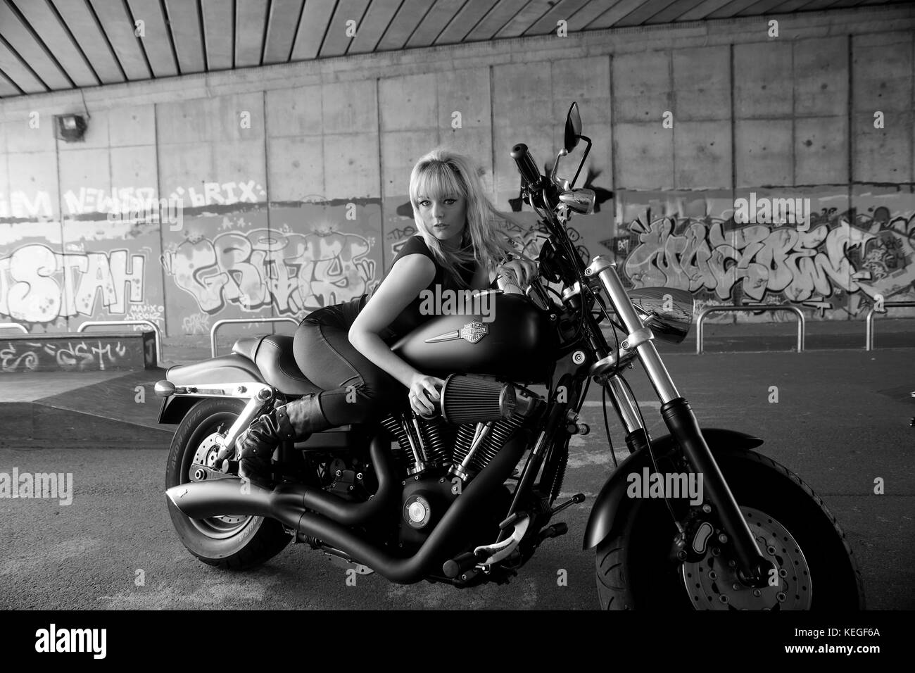 Schöne blonde Mädchen in Schwarz mit einem Harley Davidson Motorrad Stockfoto