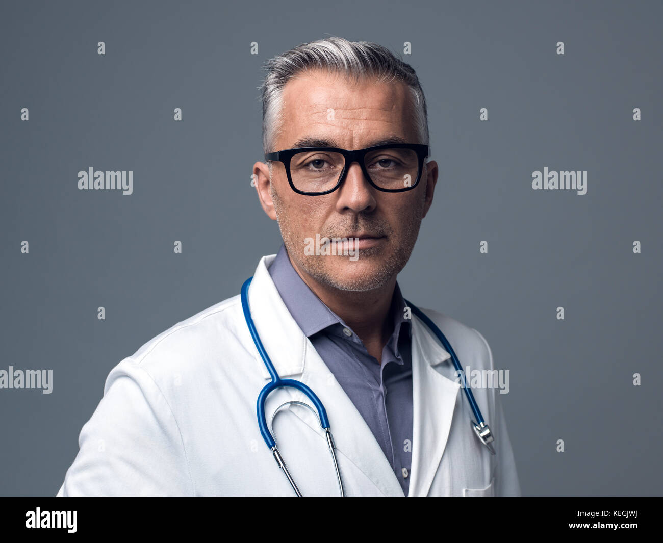 Zuversichtlich Chefarzt auf grauem Hintergrund, Medizin und Gesundheitswesen Konzept posing Stockfoto