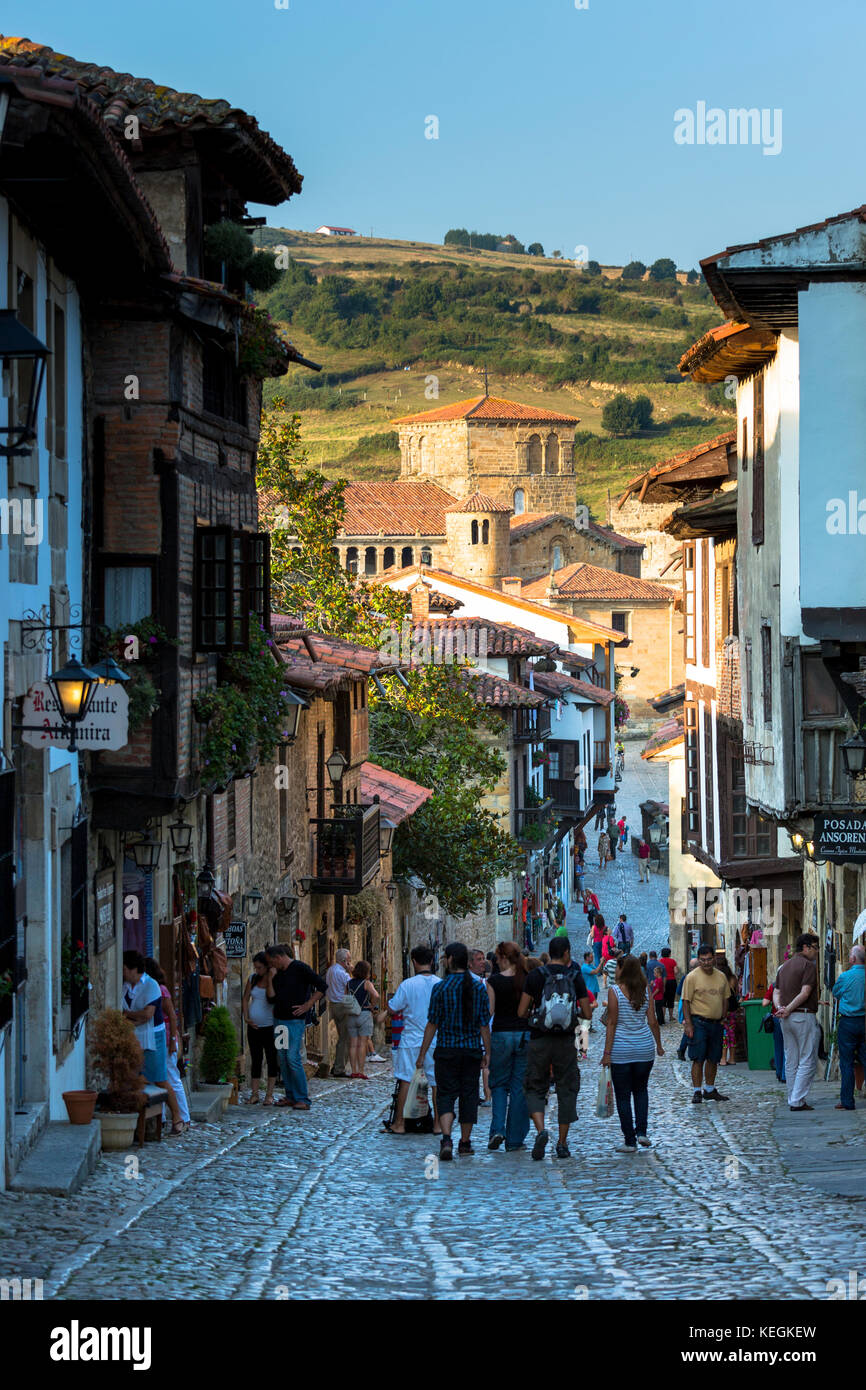 Touristen gehen vorbei an mittelalterlichen Gebäuden entlang der gepflasterten Straße Calle Del Kanton in Santillana del Mar, Kantabrien, Nordspanien Stockfoto