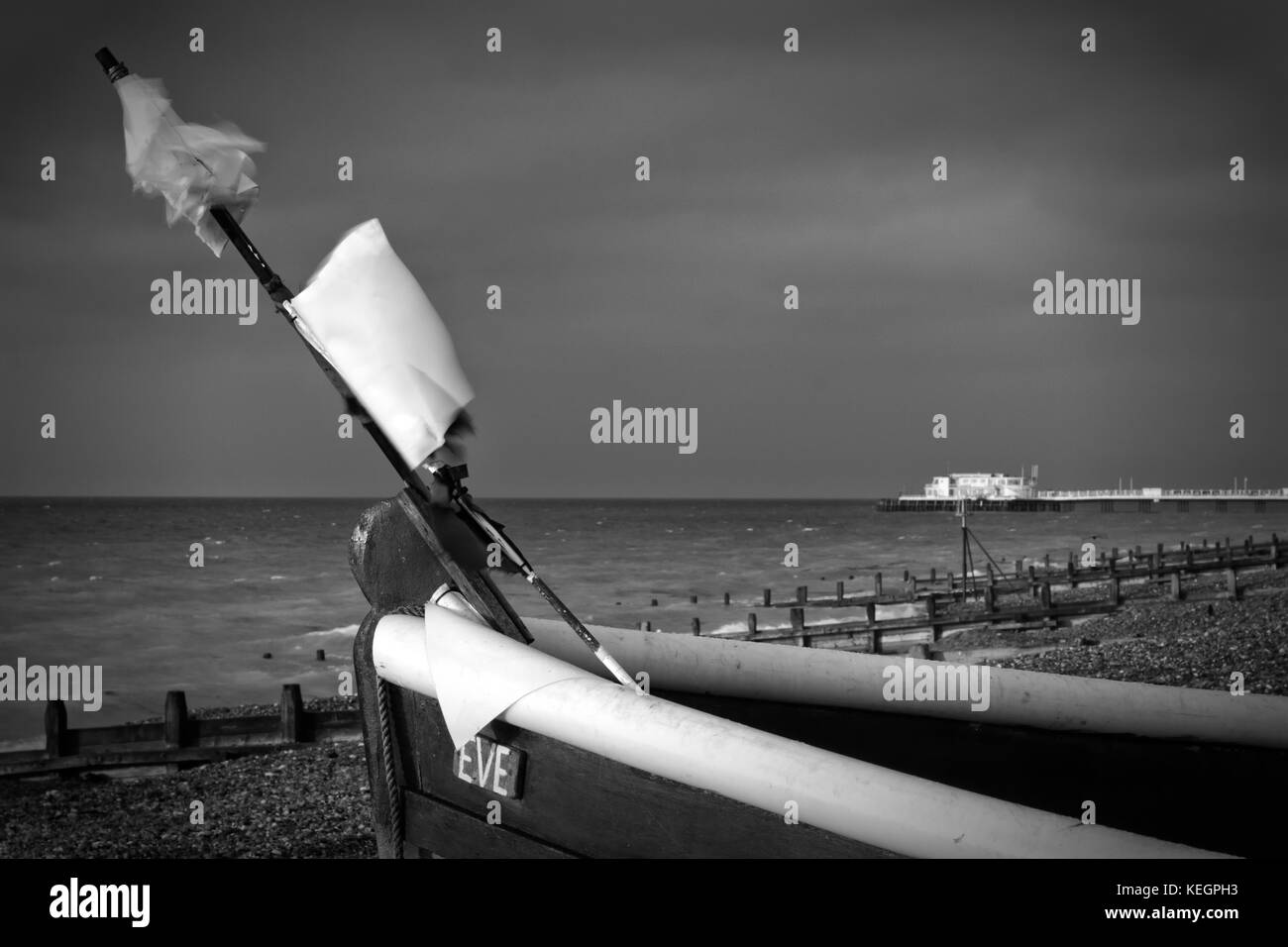 Worthing, Sussex, Großbritannien; 15. Oktober 2017; Schwarz-Weiß-Bild des Fischerboots am Strand mit Pier dahinter Stockfoto
