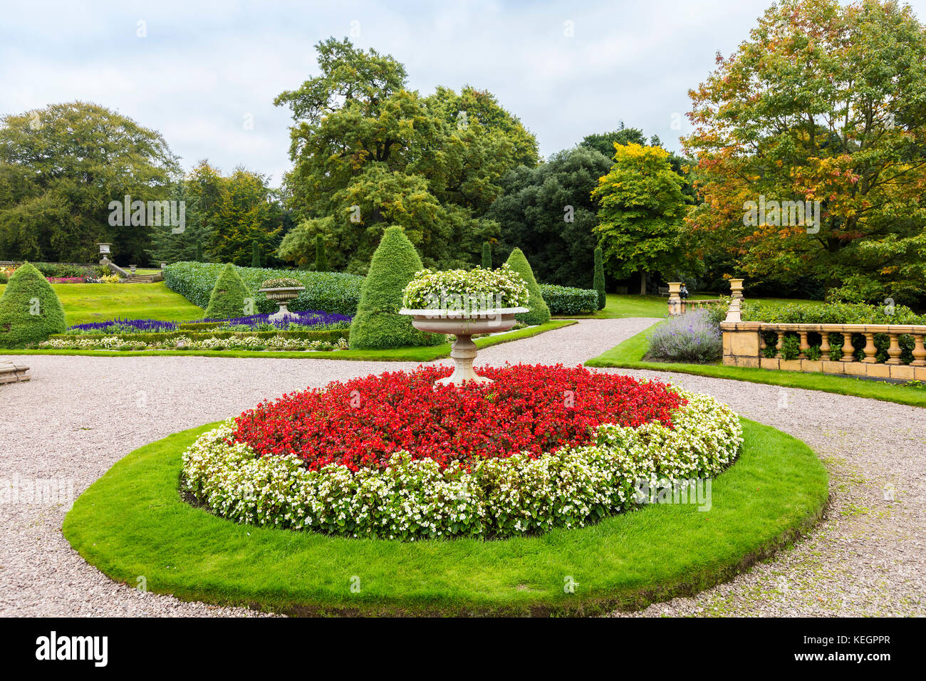 Große runde Blume mit Stein Pflanzmaschine und roten und weißen Begonien in einem Landschaftspark. Stockfoto