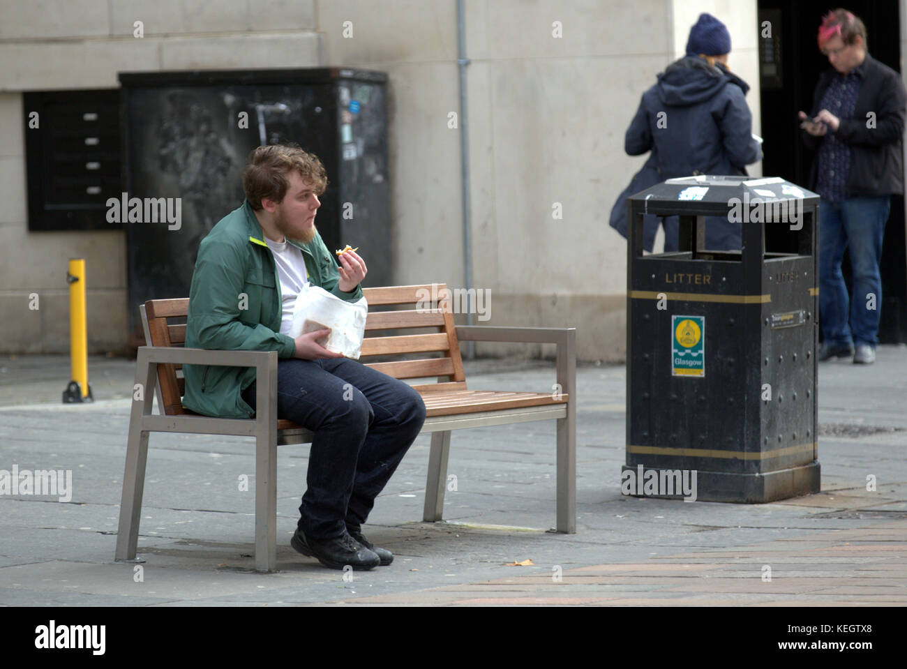 Single Mann auf einer Bank sitzen Essen nehmen Sie Junk Food in Runde auf der Buchanan Street Glasgow den Stil Meile Stockfoto