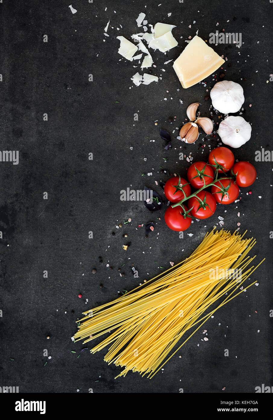 Essen Rahmen. pasta Zutaten. cherry-Tomaten, Spaghetti Pasta, Knoblauch, Basilikum, Parmesan und Gewürzen auf Dark grunge Hintergrund, Kopieren, Ansicht von oben Stockfoto