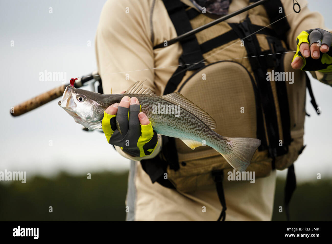 Kaukasischer Mann hält Angelrute und Fisch Stockfoto