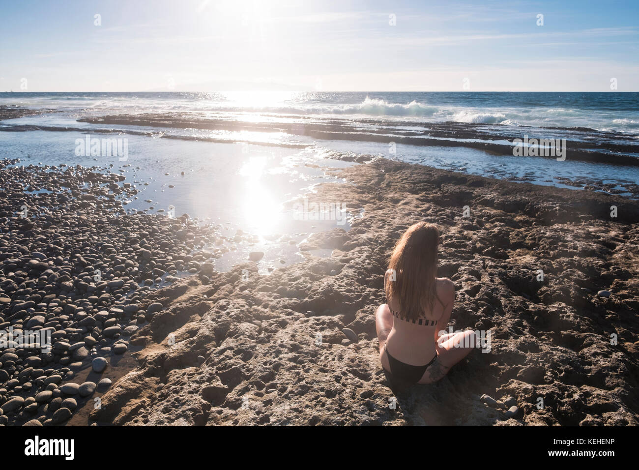 Kaukasische Frau sitzt am Strand in Bikini Stockfoto