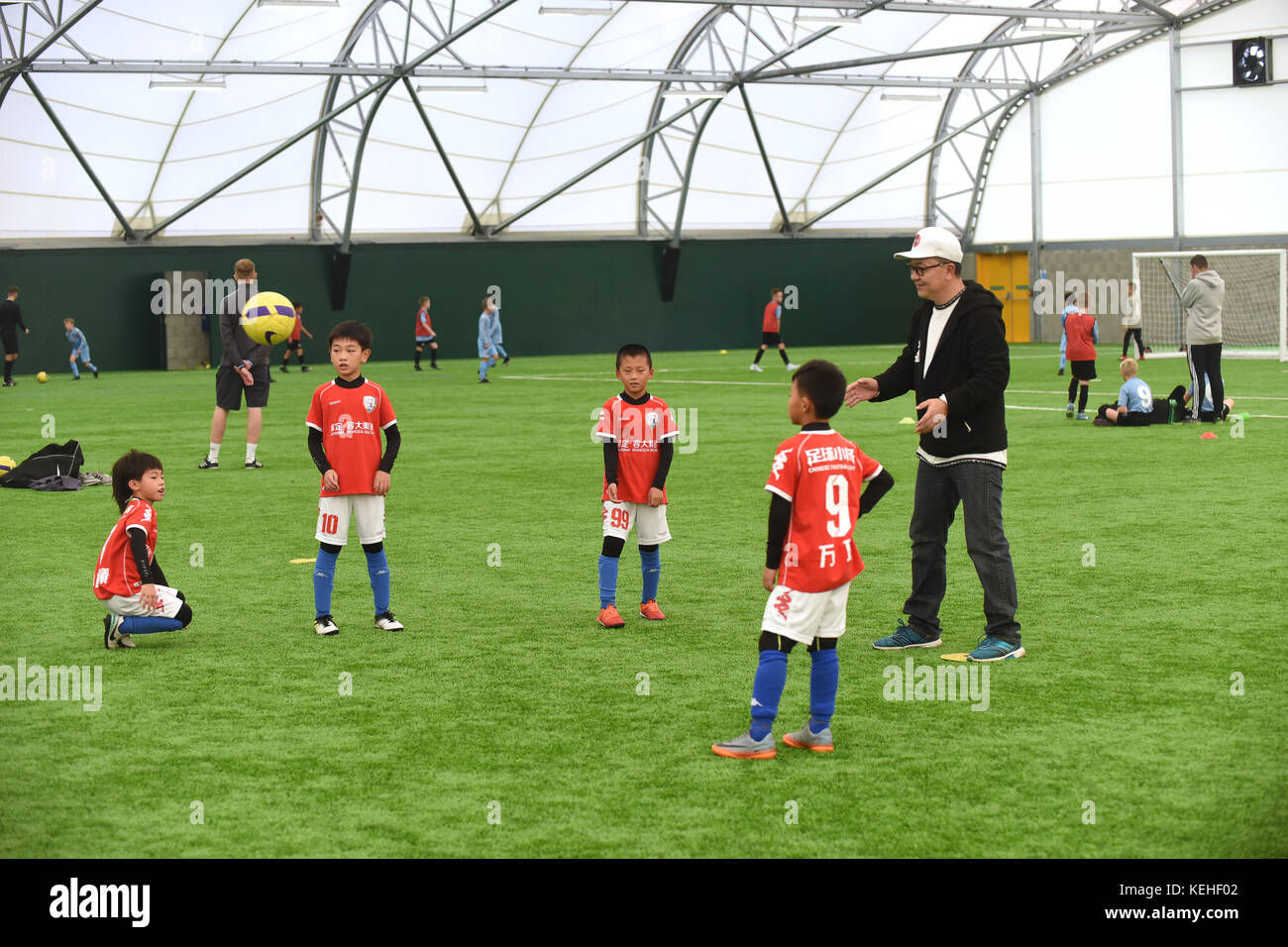 Chinesische Fußball-Kommentator Dong Lu Coaching' China Fußball Jungen unter 9 von 5 beiseite Fußballmannschaft auf ihrer Tour von Großbritannien Stockfoto